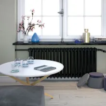 Kaloryfer pomalowany odcieniem Black z kolekcji Beckers Designer Universal. Ściana w salonie w kolorze Healing Grey z palety Beckers Designer Colour